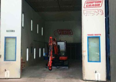 A trench digging machine in a spray booth after being spray painted and then baked in the oven